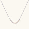 Luna pearl arc necklace in silver-tone on cream background