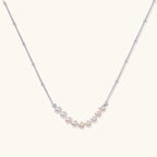 Luna pearl arc necklace in silver-tone on cream background