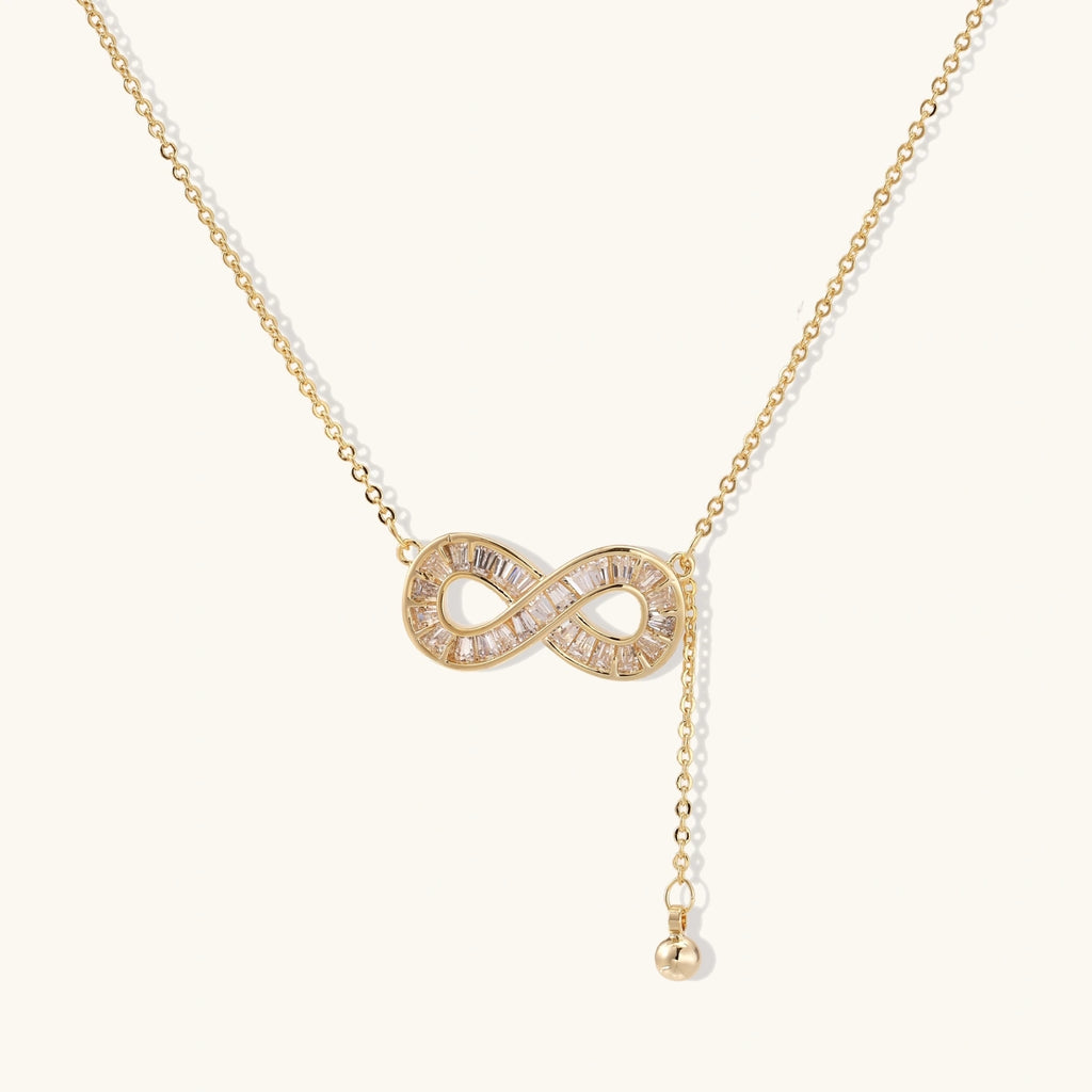 Infinity sparkle necklace in gold-tone on cream background