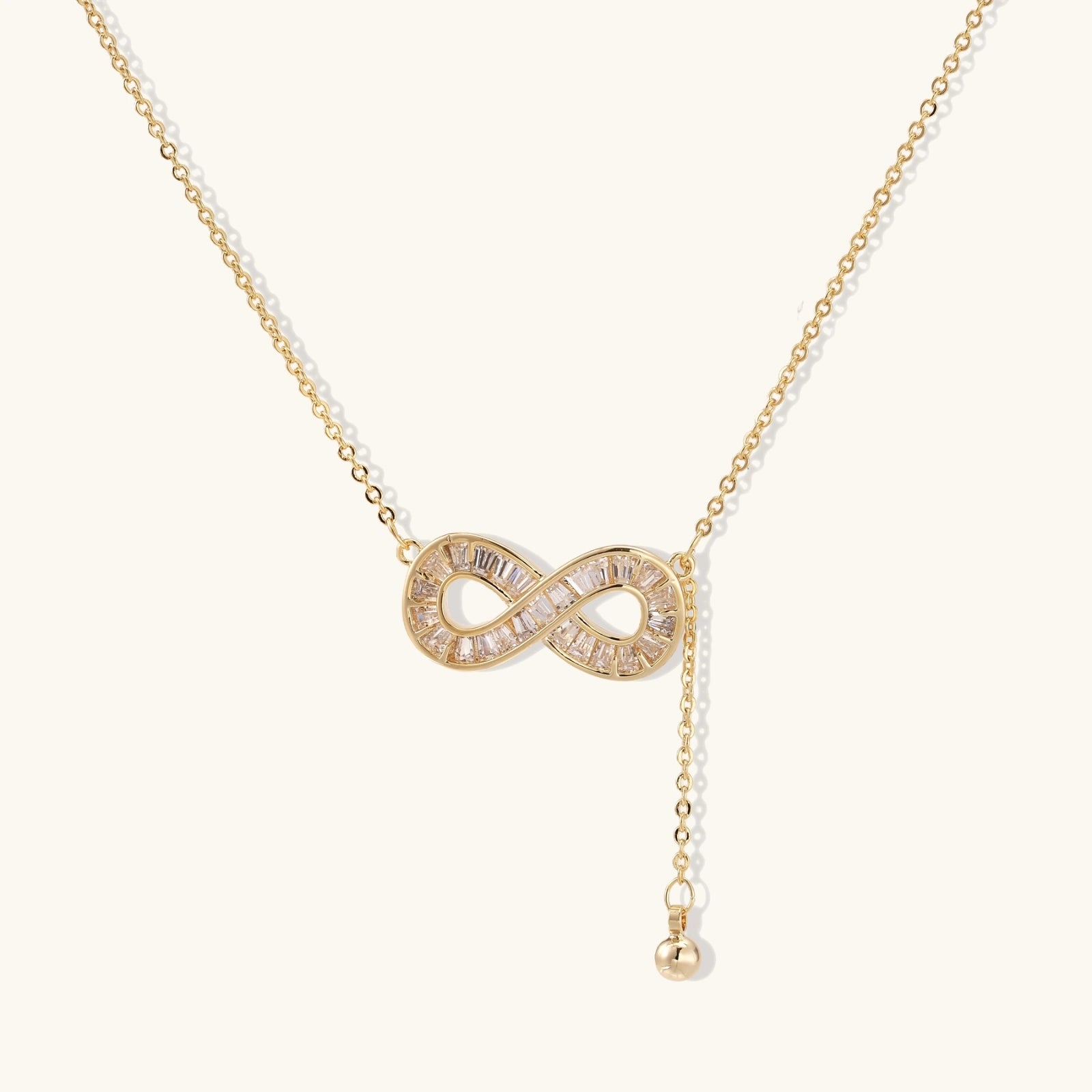 Infinity sparkle necklace in gold-tone on cream background