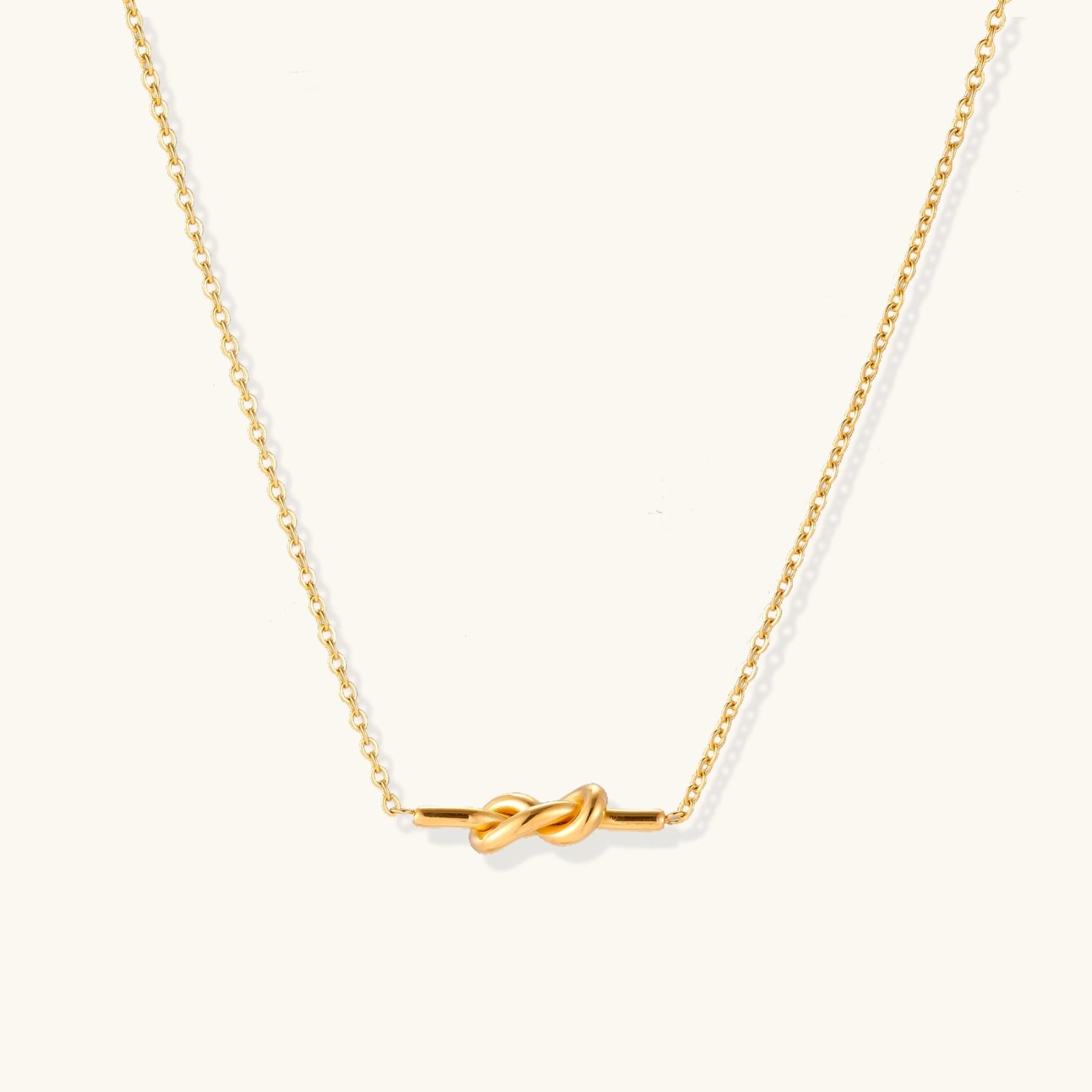 Gold-tone infinity knot necklace on delicate chain