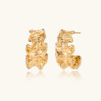Gold-tone wave-textured hoop earrings on white background