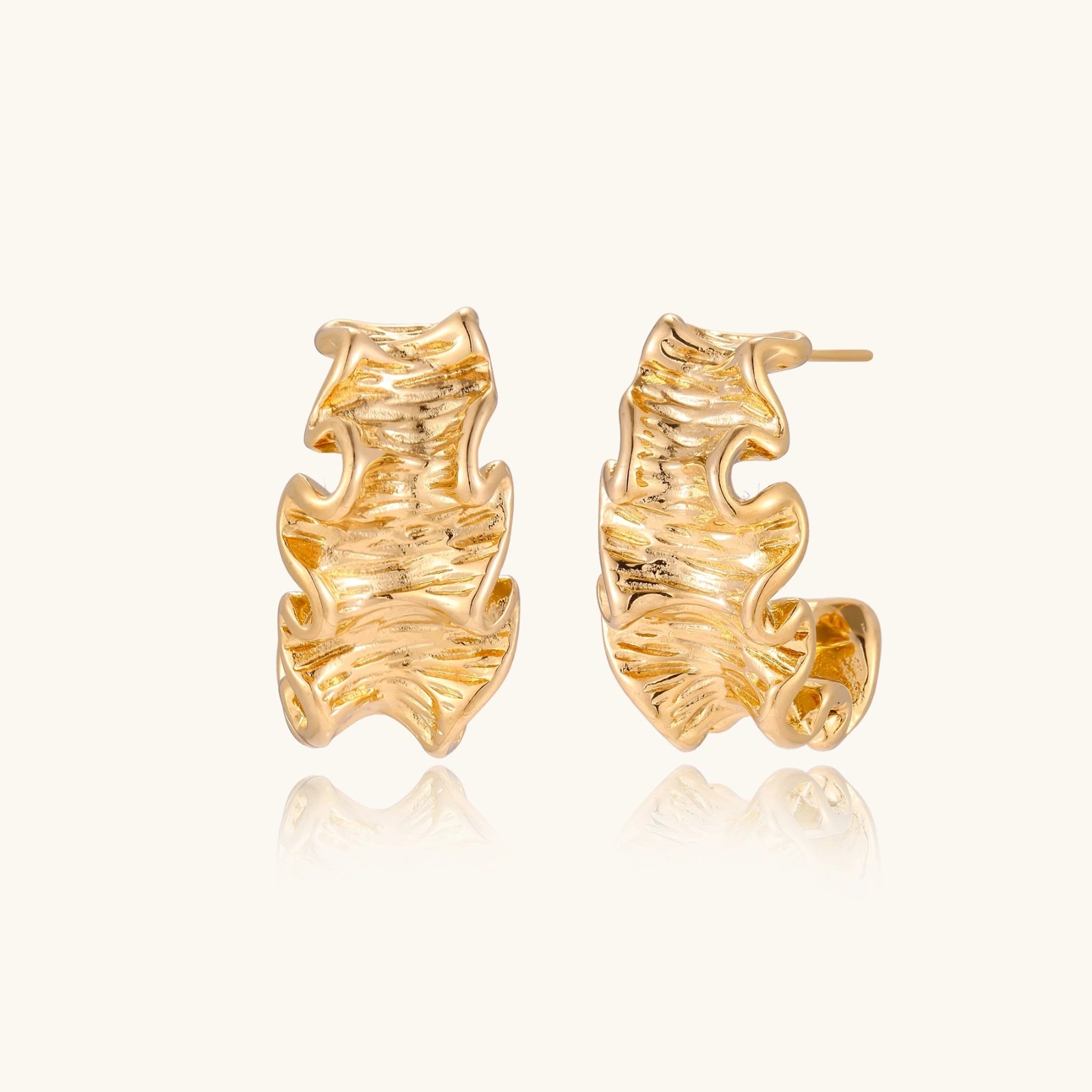 Gold-tone wave-textured hoop earrings on white background