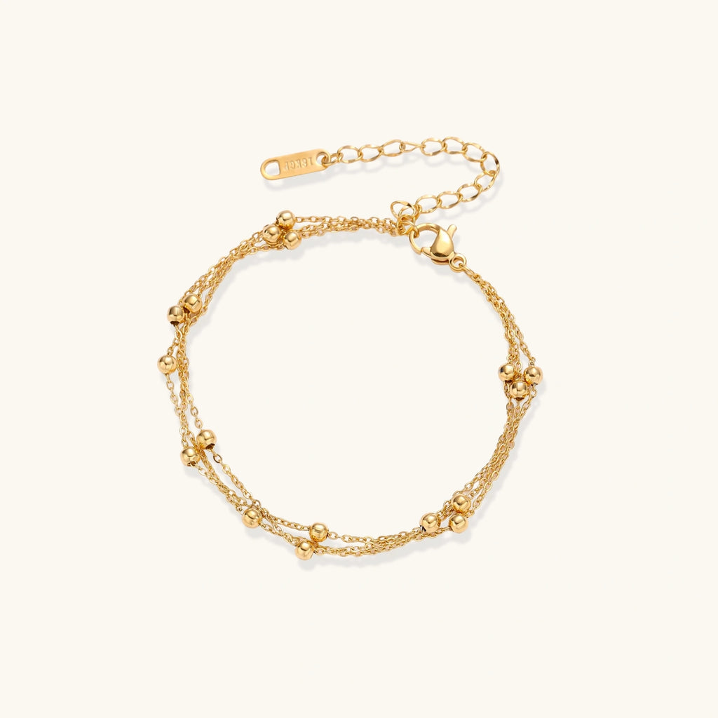 Gold-tone triple-strand beaded bracelet on cream background