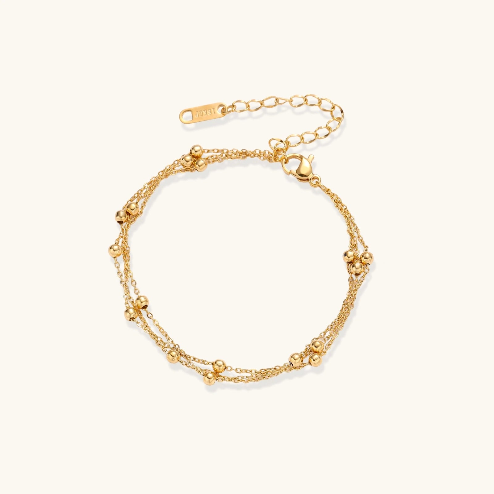 Gold-tone triple-strand beaded bracelet on cream background