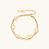 Gold-tone clover and star charm bracelet on cream background