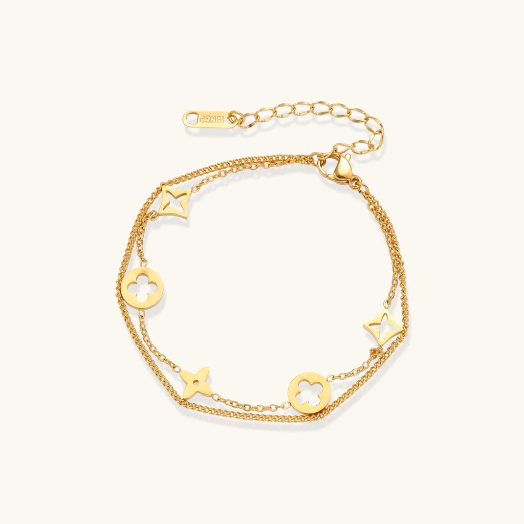 Gold-tone clover and star charm bracelet on cream background
