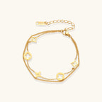 Gold-tone clover and star charm bracelet on cream background