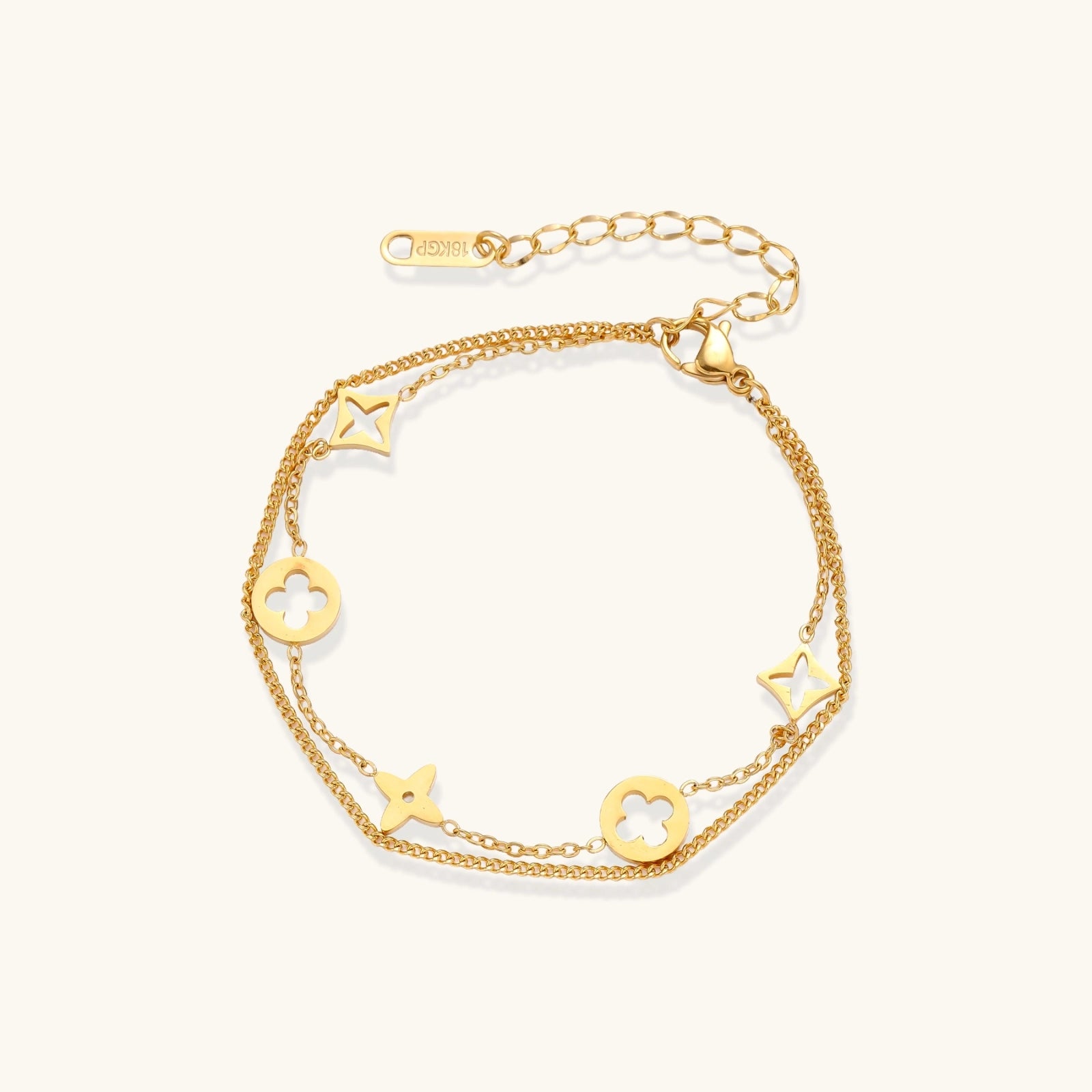 Gold-tone clover and star charm bracelet on cream background