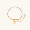 Gold-tone Good Luck engraved chain bracelet on cream background