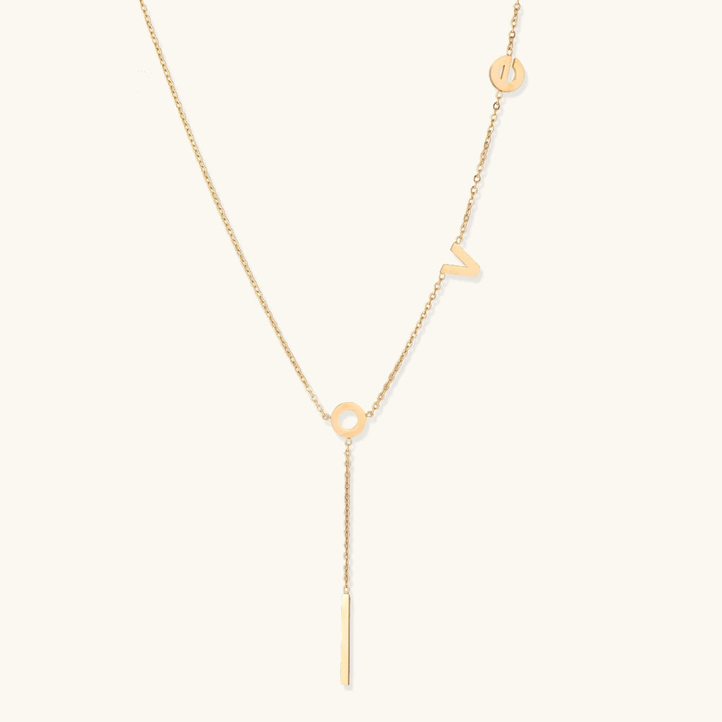Gold-tone LOVE lariat Y-drop necklace on cream background