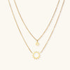 Gold-tone sun and smiley layered necklace on white background