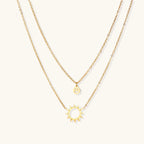 Gold-tone sun and smiley layered necklace on white background