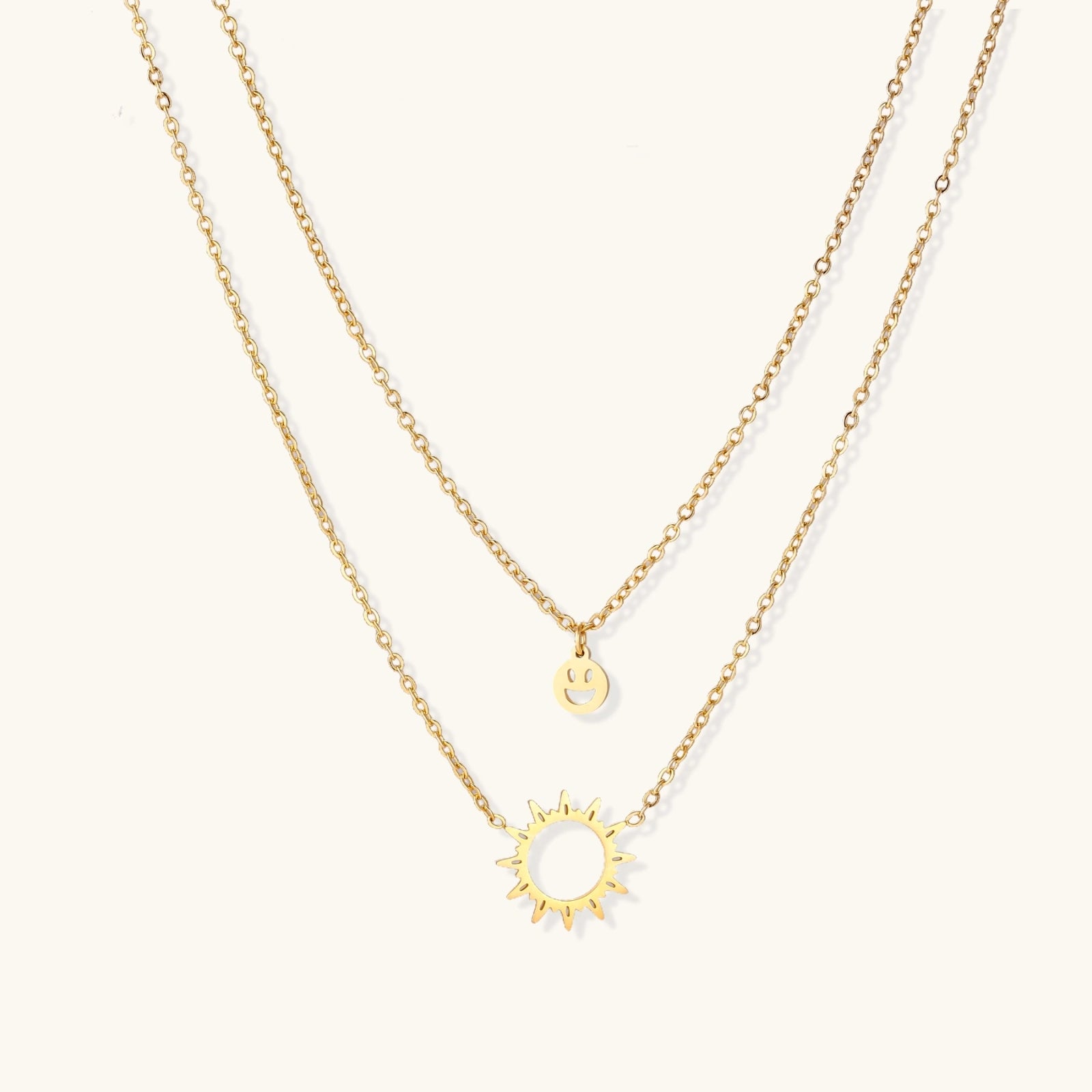 Gold-tone sun and smiley layered necklace on white background