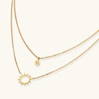 Sunburst and smiley gold-tone layered necklace close-up