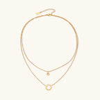 Layered gold-tone charm necklace detail