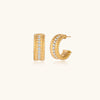 Chunky textured gold-tone hoop earrings on cream background