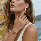 Gold-tone clover charm bracelet styled with a stack