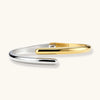 Two-tone gold and silver bypass cuff bracelet on white background