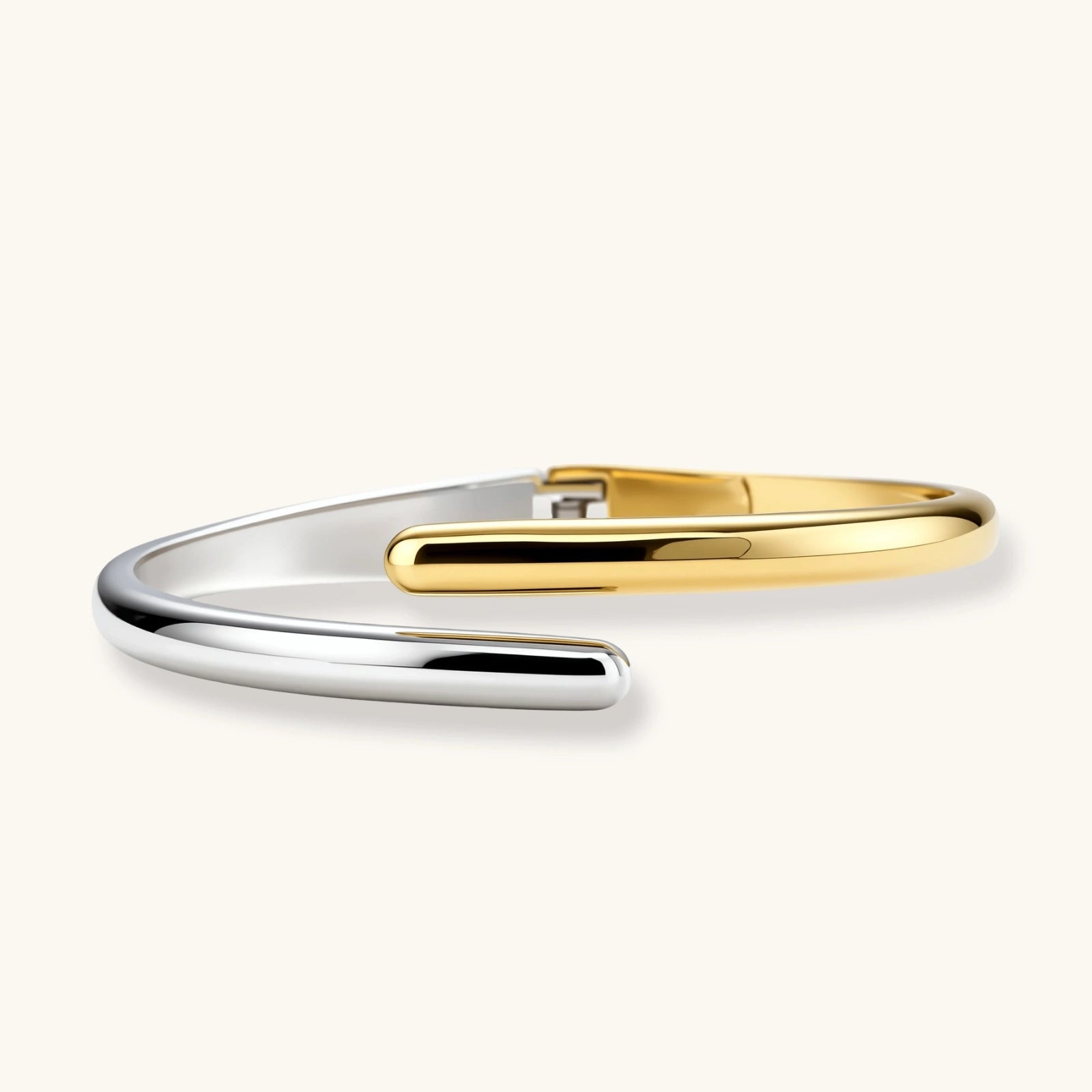 Two-tone gold and silver bypass cuff bracelet on white background