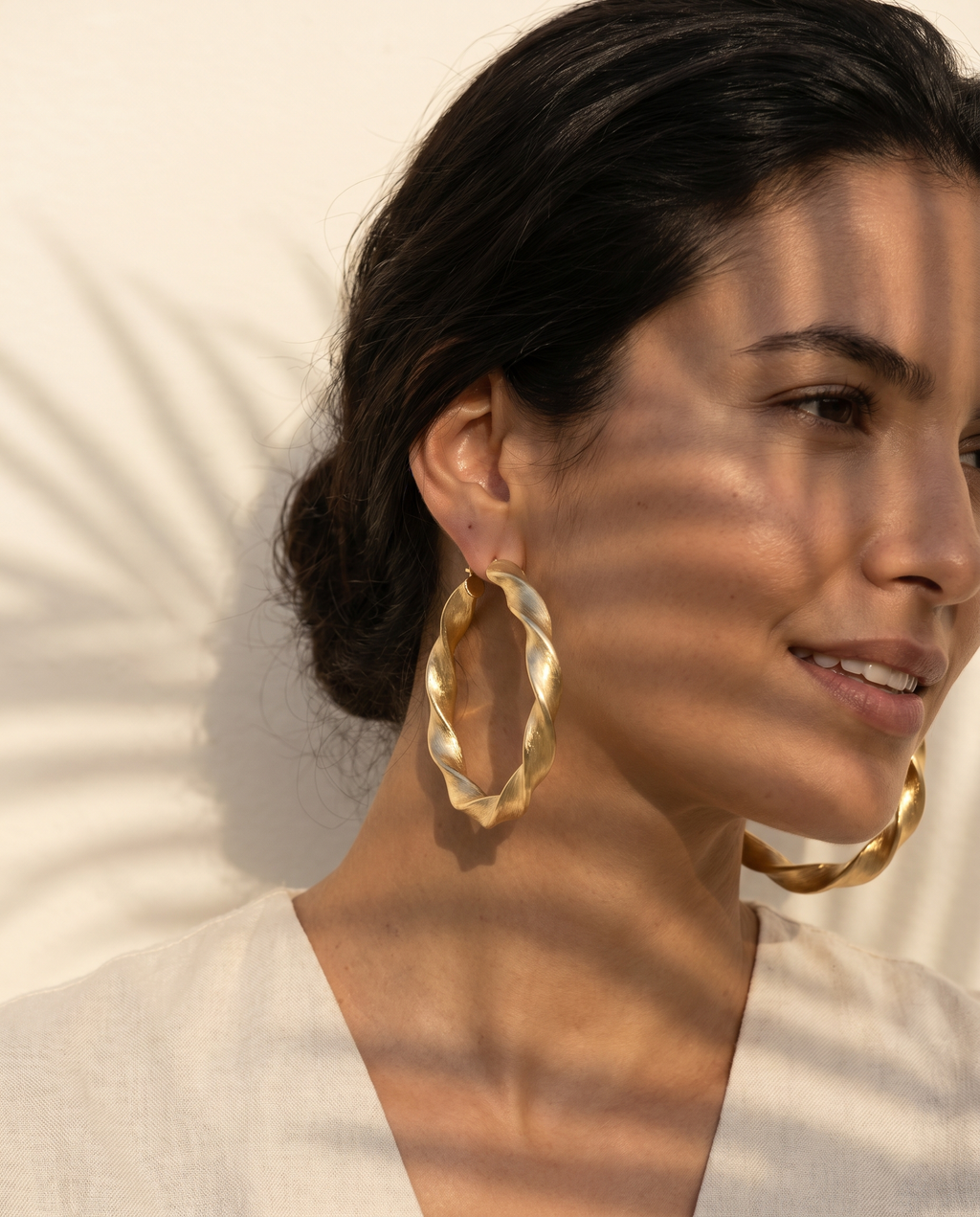 Ribbed gold-tone hoops worn in warm sunlight